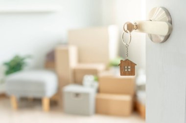Moving house, relocation. The key was inserted into the door of the new house, inside the room was a cardboard box containing personal belongings and furniture. move in the apartment or condominium