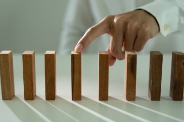 Domino 'yu elleri olan sigorta korur. İş adamı elleri iş krizinde domino taşlarının düşmesini durdurur. işletme risk denetimi ve planlama ve işletmeler sigorta işletmelerini önlemek için stratejiler.