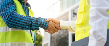 İnşaat ekibi el sıkışıyor. Başlangıç planı. İnşaat alanı, endüstri, mimari, ortak, takım çalışması, anlaşma, mülkiyet, irtibat merkezindeki yeni proje sözleşmesi..