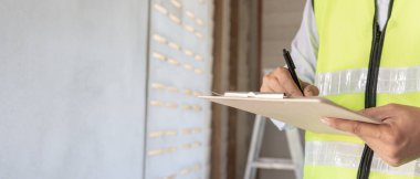 inspector or engineer is inspecting construction and quality assurance new house using a checklist. Engineers or architects or contactor work to build the house before handing it over to the homeowner