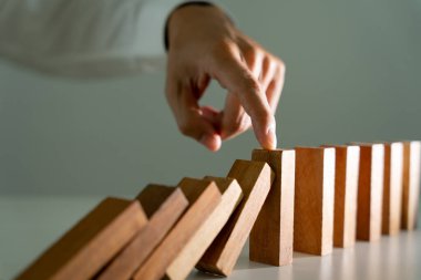Domino 'yu elleri olan sigorta korur. İş adamı elleri iş krizinde domino taşlarının düşmesini durdurur. işletme risk denetimi ve planlama ve işletmeler sigorta işletmelerini önlemek için stratejiler.