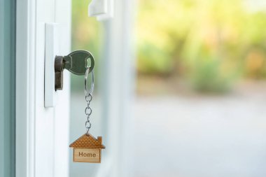 Landlord key for unlocking house is plugged into the door. Second hand house for rent and sale. keychain is blowing in the wind. mortgage for new home, buy, sell, renovate, investment, owner, estate