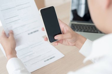 business man use phone to scan barcode or QR codes to pay credit card bill after receiving document invoice online. payment, receive, paying electricity, digital payments without money, technology