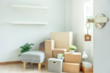 Moving house, relocation. The key was inserted into the door of the new house, inside the room was a cardboard box containing personal belongings and furniture. move in the apartment or condominium