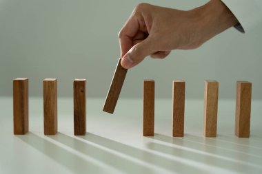 Domino 'yu elleri olan sigorta korur. İş adamı elleri iş krizinde domino taşlarının düşmesini durdurur. işletme risk denetimi ve planlama ve işletmeler sigorta işletmelerini önlemek için stratejiler.