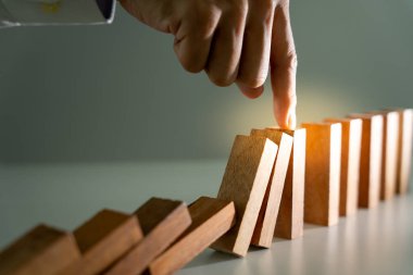 Domino 'yu elleri olan sigorta korur. İş adamı elleri iş krizinde domino taşlarının düşmesini durdurur. işletme risk denetimi ve planlama ve işletmeler sigorta işletmelerini önlemek için stratejiler.