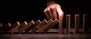 Domino 'yu elleri olan sigorta korur. İş adamı elleri iş krizinde domino taşlarının düşmesini durdurur. işletme risk denetimi ve planlama ve işletmeler sigorta işletmelerini önlemek için stratejiler.