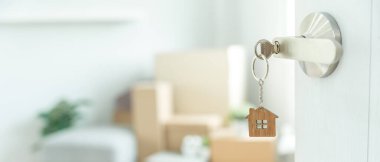 Moving house, relocation. The key was inserted into the door of the new house, inside the room was a cardboard box containing personal belongings and furniture. move in the apartment or condominium