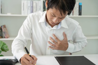 Göğüs kafesinde kalp krizi belirtileri var. Asyalı bir adamın göğüs ağrısı var. Kalp rahatsızlığı, sızıntı, genişleme, kalp büyümesi, göğsüne acı veren bir ifadeyle bastırma.