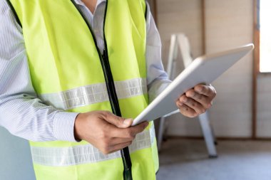 Müfettiş ya da mühendis, tablet kullanarak yeni ev inşaatını ve kalite güvencesini denetliyor. Mühendisler, mimarlar ya da irtibat görevlileri ev sahibine teslim etmeden önce evi inşa etmek için çalışıyorlar.