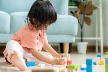 Mutlu Asya çocukları oyuncak bloklarıyla oynayıp öğreniyor. Aile evde mutlu ve heyecanlı. Kızın zaman, etkinlik, gelişme, IQ, EQ, meditasyon, beyin, kaslar, temel beceriler.