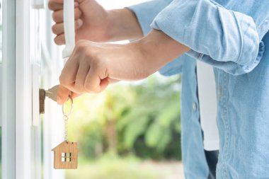 Evin kilidini açmak için ev sahibi anahtarı kapıya takılı. Kira ve satış için ikinci el ev. Sahibi el ile yeni ev için kapı ipoteğini açar, satın alır, satar, yeniler, yatırım, sahip, estat