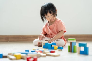 Mutlu Asya çocukları oyuncak bloklarıyla oynayıp öğreniyor. Aile evde mutlu ve heyecanlı. Kızın zaman, etkinlik, gelişme, IQ, EQ, meditasyon, beyin, kaslar, temel beceriler.