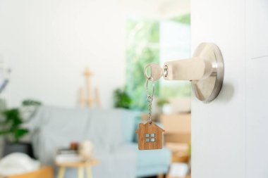 Moving house, relocation. The key was inserted into the door of the new house, inside the room was a cardboard box containing personal belongings and furniture. move in the apartment or condominium