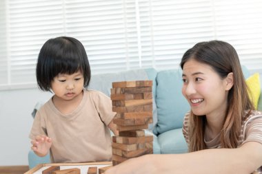 Asya 'lı mutlu anne küçük kızla Jan-ga oyunu oynuyor. Komik aile evde mutlu ve heyecanlı. Anne ve oğlu birlikte vakit geçiriyorlar. Tatil, hafta sonu, boş.