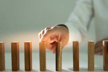 Domino 'yu elleri olan sigorta korur. İş adamı elleri iş krizinde domino taşlarının düşmesini durdurur. işletme risk denetimi ve planlama ve işletmeler sigorta işletmelerini önlemek için stratejiler.