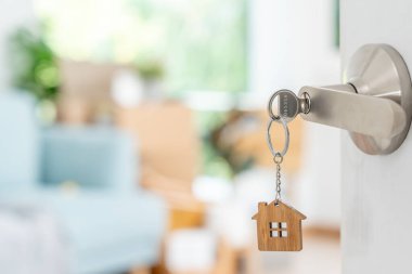 Moving house, relocation. The key was inserted into the door of the new house, inside the room was a cardboard box containing personal belongings and furniture. move in the apartment or condominium