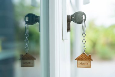 Landlord key for unlocking house is plugged into the door. Second hand house for rent and sale. keychain is blowing in the wind. mortgage for new home, buy, sell, renovate, investment, owner, estate