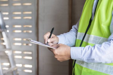 inspector or engineer is inspecting construction and quality assurance new house using a checklist. Engineers or architects or contactor work to build the house before handing it over to the homeowner