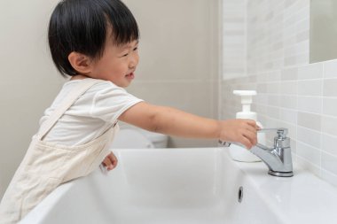 Su tasarrufu. Küçük çocuk çevreyi korumak için tuvaletteki suyu kapatıp duruyor. Yeşillenen gezegen, küresel ısınmayı azalt Dünya 'yı, yaşamı, geleceği, risk enerjisini, krizi, su gününü kurtar