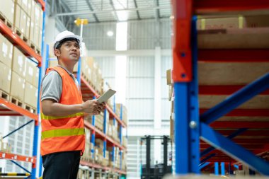 Depo çalışanı, envanterde ve stok ürünlerinde kutu ürünlerini kontrol ediyor. Lojistik ticaret nakliyat ve teslimat müşterilere, denetim, depo, depo, fabrika.