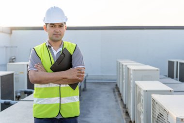 Asyalı bakım mühendisi portresi fabrikanın çatısında çalışıyor. Müteahhit kompresör sistemini denetleyecek ve inşaatta havalandırma sistemi kurmayı planlıyor. teknoloji