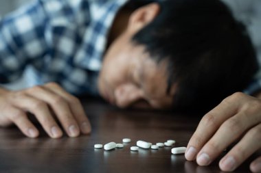 Asyalı erkek aşırı dozda hap kullanıyor, stresli, üzgün, uyuşturucu bağımlısı, uyuşturucu bağımlısı, hasta, sağlıksız, mutsuz, intihar, depresyonda veya umutsuz, uyuşturucu bağımlısı, yaşam ve aile sorunları, motivasyonsuz