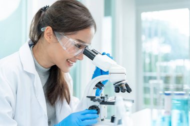 Bilimadamı ileri bilimsel laboratuvarda biyokimyasal örnekleri analiz ediyor. Tıbbi profesyonel kullanım mikroskobu virüsün mikrobiyolojik gelişimini gösteriyor. Fen laboratuvarında biyoteknoloji araştırması.