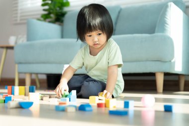Mutlu Asyalı çocuk oyun oynuyor ve oyuncak bloklarını öğreniyor. Çocuklar evde çok mutlu ve heyecanlı. Çocuk oyun, etkinlik, gelişme ve dikkat eksikliği hiperaktivite bozukluğuyla çok iyi vakit geçiriyor