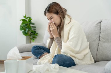 sick woman with a headache sitting under blanket, female sneezing and runny nose with seasonal influenza, allergic, high fever and influenza, resting, virus, coronavirus, feel illness, respiratory