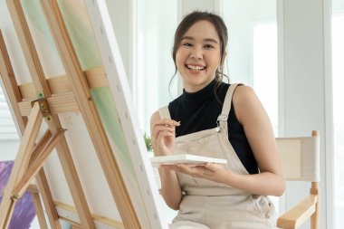 beautiful female hobbies about artist and use paintbrush in abstract art for create masterpiece. painter paint with watercolors or oil in studio house. enjoy painting as hobby, recreation, inspiration