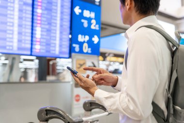 İş adamı, internet başvurusu üzerinden uçak bileti almak için cep telefonu kullanıyor. Seyahat saatlerini kontrol ediyor. Seyahat, seyahat, ödeme, vade, rezervasyon, online kayıt.