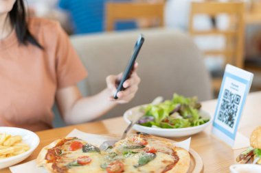 Woman use smartphone to scan QR code to pay in cafe restaurant with a digital payment without cash. Choose menu and order accumulate discount. E wallet, technology, pay online, credit card, bank app.
