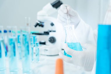 Bilimadamı ileri bilimsel laboratuvarda biyokimyasal örnekleri analiz ediyor. Tıp, kozmetiğin fiziksel özelliklerini test etmek için kimyasalları karıştırıyor. viral gelişim. Fen laboratuvarında biyoteknoloji araştırması