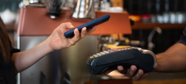 Kadın, kafeteryada nakit olmadan dijital ödeme yaparak kredi kartı ödemesini internet üzerinden yapıyor. İndirim biriktir. E cüzdan, teknoloji, online ödeme, kredi kartı, banka uygulaması. günlük yaşam ödemesi