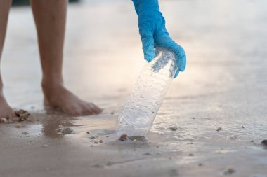 Su tasarrufu. Gönüllü olarak plajdaki çöpleri topluyor ve plastik şişeler suda yaşayan canlılara zarar gelmesini engelliyor. Dünya, Çevre, Yeşilci Gezegen, küresel ısınmayı azaltmak, Dünya 'yı kurtarmak