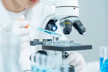 Bilimadamı ileri bilimsel laboratuvarda biyokimyasal örnekleri analiz ediyor. Tıbbi profesyonel kullanım mikroskobu virüsün mikrobiyolojik gelişimini gösteriyor. Fen laboratuvarında biyoteknoloji araştırması