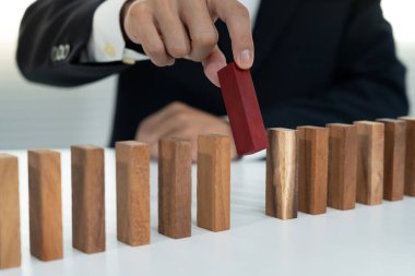 Domino 'yu elleri olan sigorta korur. İş adamı elleri iş krizinde domino taşlarının düşmesini durdurur. işletme risk denetimi ve planlama ve işletmeler sigorta işletmelerini önlemek için stratejiler.