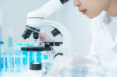 Bilimadamı ileri bilimsel laboratuvarda biyokimyasal örnekleri analiz ediyor. Tıbbi profesyonel kullanım mikroskobu virüsün mikrobiyolojik gelişimini gösteriyor. Fen laboratuvarında biyoteknoloji araştırması.