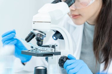 Bilimadamı ileri bilimsel laboratuvarda biyokimyasal örnekleri analiz ediyor. Tıbbi profesyonel kullanım mikroskobu virüsün mikrobiyolojik gelişimini gösteriyor. Fen laboratuvarında biyoteknoloji araştırması.
