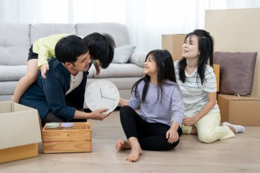 Taşınmak, taşınmak. Aile gülümsemesi ve yeni bir daire aldıktan sonra mutlu olmak, odanın içinde kişisel eşyalar ve mobilyalar içeren bir karton kutu vardı. yeni daireye taşınmak ya da taşınmak