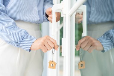 Evin kilidini açmak için ev sahibi anahtarı kapıya takılı. Kira ve satış için ikinci el ev. Sahibi yeni ev, satın al, sat, yenile, yatırım, sahip, mülk