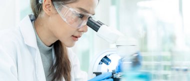 Bilimadamı ileri bilimsel laboratuvarda biyokimyasal örnekleri analiz ediyor. Tıbbi profesyonel kullanım mikroskobu virüsün mikrobiyolojik gelişimini gösteriyor. Fen laboratuvarında biyoteknoloji araştırması.