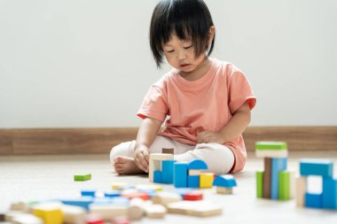 Mutlu Asyalı çocuk oyun oynuyor ve oyuncak bloklarını öğreniyor. Çocuklar evde çok mutlu ve heyecanlı. Çocuk oyun, etkinlik, gelişme ve dikkat eksikliği hiperaktivite bozukluğuyla çok iyi vakit geçiriyor