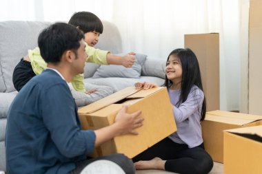 Taşınmak, taşınmak. Aile gülümsemesi ve yeni eve taşındıktan sonra birlikte oyun oynardık. Odanın içinde kişisel eşyalar ve mobilyalar içeren bir karton kutu vardı. Yeni daireye taşın, apartman dairesi.