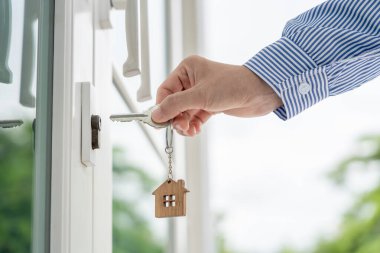Evin kilidini açmak için ev sahibi anahtarı kapıya takılı. Kira ve satış için ikinci el ev. Sahibi el ile yeni ev için kapı ipoteğini açar, satın alır, satar, yeniler, yatırım, sahip, estat