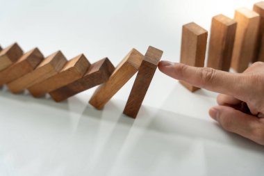 Domino 'yu elleri olan sigorta korur. İş adamı elleri iş krizinde domino taşlarının düşmesini durdurur. işletme risk denetimi ve planlama ve işletmeler sigorta işletmelerini önlemek için stratejiler