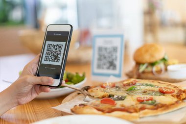 Woman use smartphone to scan QR code to pay in cafe restaurant with a digital payment without cash. Choose menu and order accumulate discount. E wallet, technology, pay online, credit card, bank app.