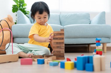 Mutlu Asyalı çocuk oyun oynuyor ve oyuncak bloklarını öğreniyor. Çocuklar evde çok mutlu ve heyecanlı. Çocuk oyun, etkinlik, gelişme ve dikkat eksikliği hiperaktivite bozukluğuyla çok iyi vakit geçiriyor