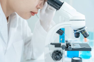 Bilimadamı ileri bilimsel laboratuvarda biyokimyasal örnekleri analiz ediyor. Tıbbi profesyonel kullanım mikroskobu virüsün mikrobiyolojik gelişimini gösteriyor. Fen laboratuvarında biyoteknoloji araştırması